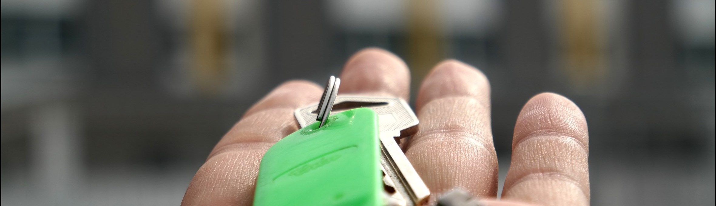 a hand holding keys in front of a row of houses 