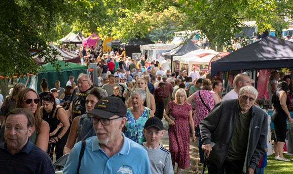A packed path of market stalls and people browsing them 