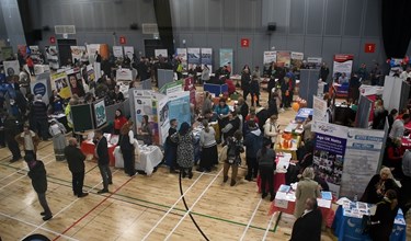 Stalls and people attending the last careers fair in a sports hall