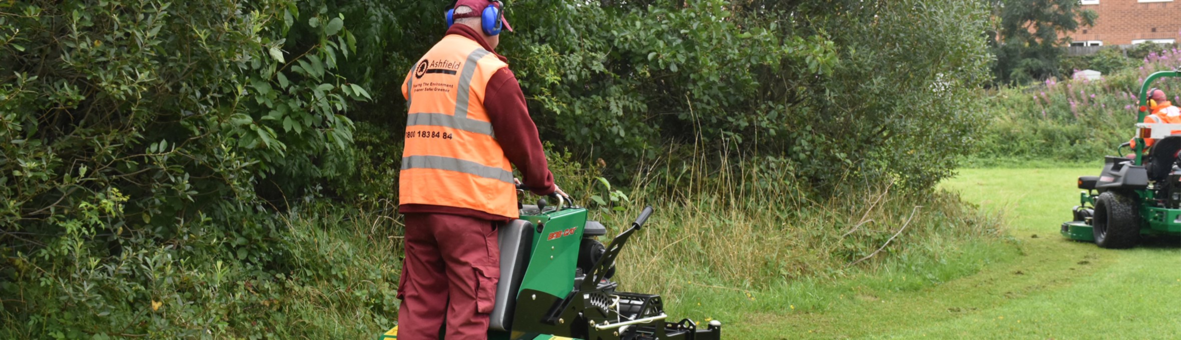 Man in ADC branded hi vis jacket using machinery to mow a field
