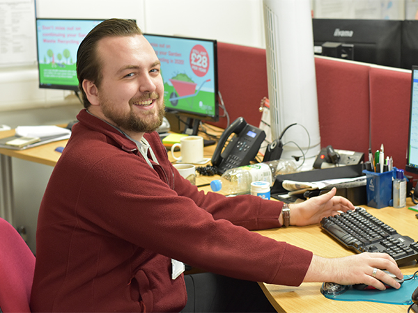 Man sat at computer desk smiling at camera
