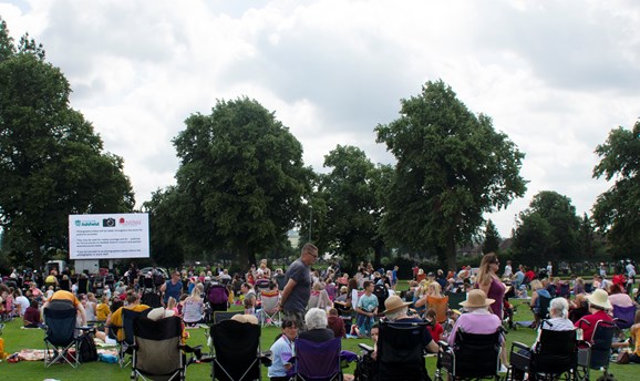 hundreds of people sitting on fold out chairs watching a big screen on Titchfield Park 