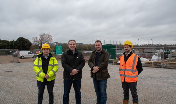 Four men smile at the camera, they are stood on the new car park 