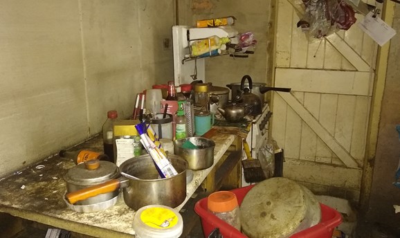 the kitchen of the property covered in grime, dirty pots and pans 