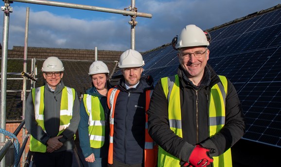 Cllr Relf smiling on a roof in front of solar panels 